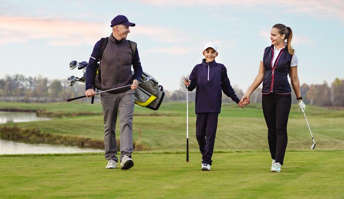 A family of three walking on a golf course